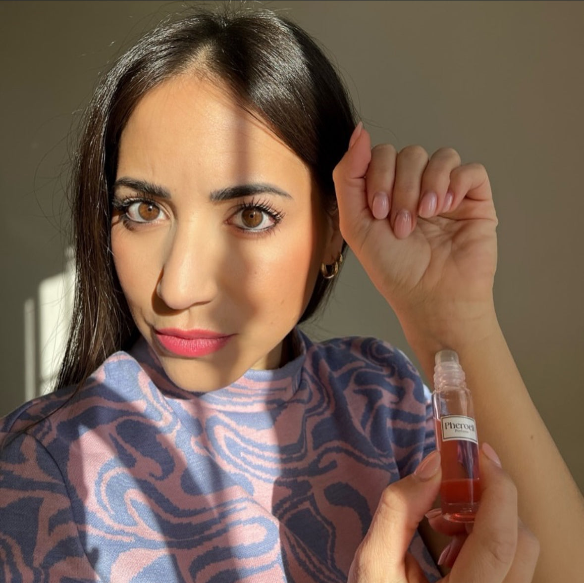 Mujer aplicándose el perfume Pheroeli en la muñeca